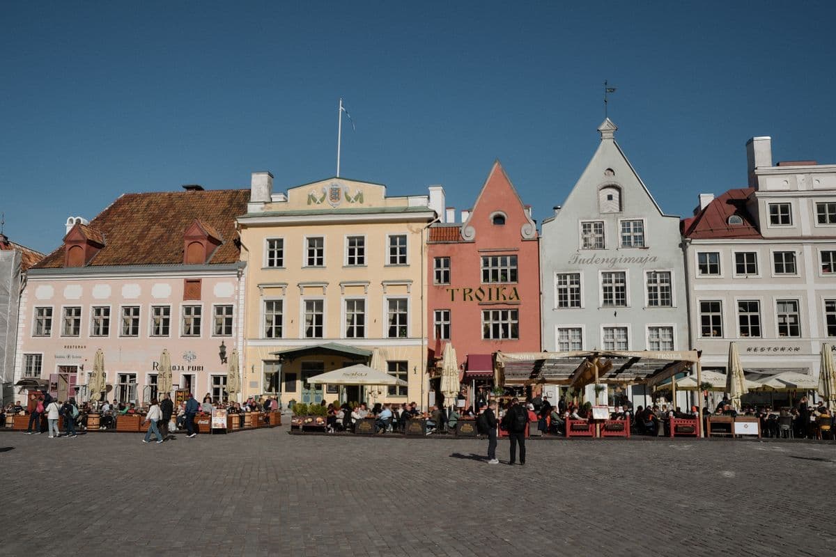 Colourful old town square with cafe terraces under a deep blue European sky
